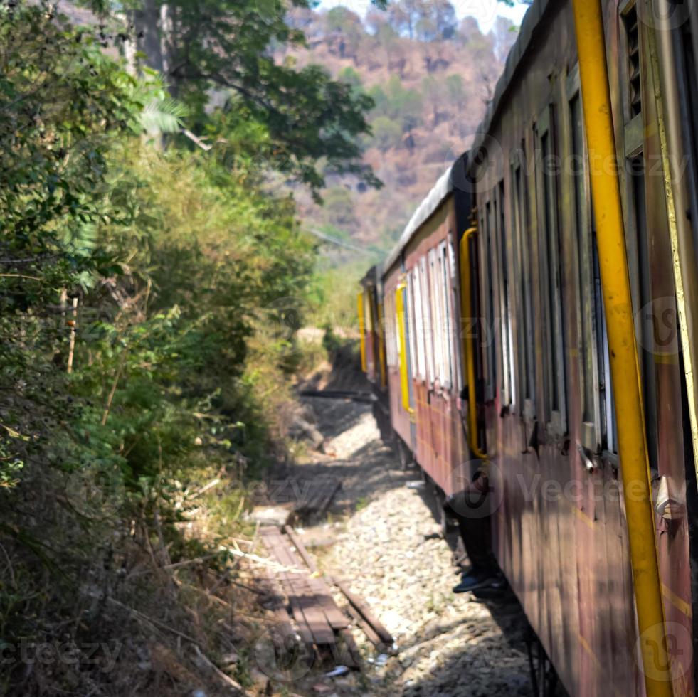 tren de juguete moviéndose en las laderas de las montañas, hermosa vista, una montaña lateral, un valle lateral moviéndose en ferrocarril hacia la colina, entre bosques naturales verdes. tren de juguete de kalka a shimla en india, tren indio foto