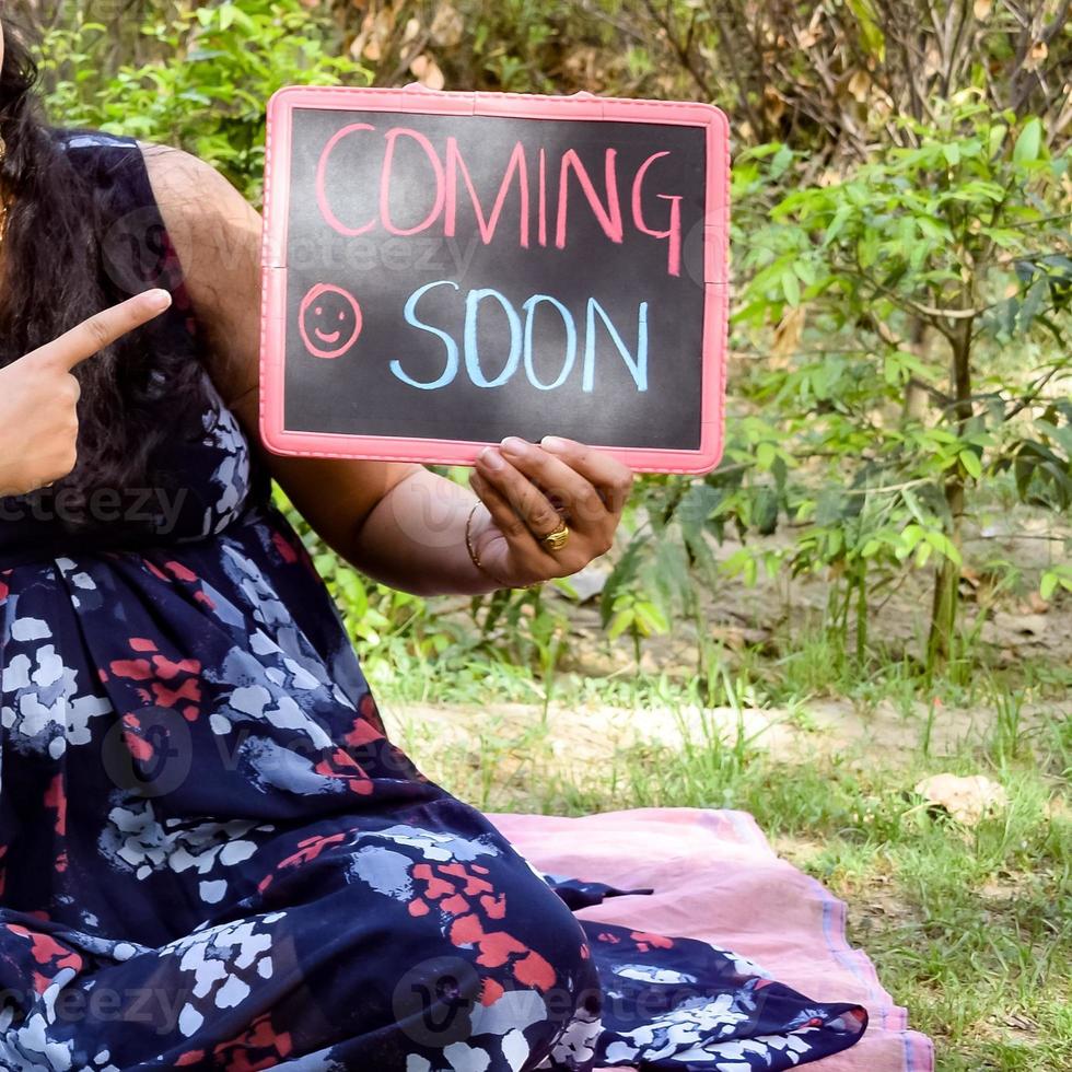 Indian couple posing for maternity baby shoot. The couple is posing in a lawn with green grass and the woman is falunting her baby bump in Lodhi Garden in New Delhi, India photo