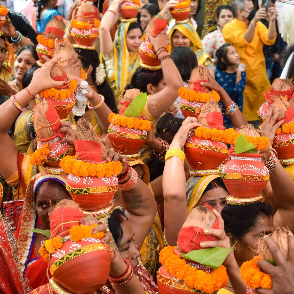 New Delhi, India April 03 2022 - Women with Kalash on head during Jagannath Temple Mangal Kalash Yatra, Indian Hindu devotees carry earthen pots containing sacred water with a coconut on top photo