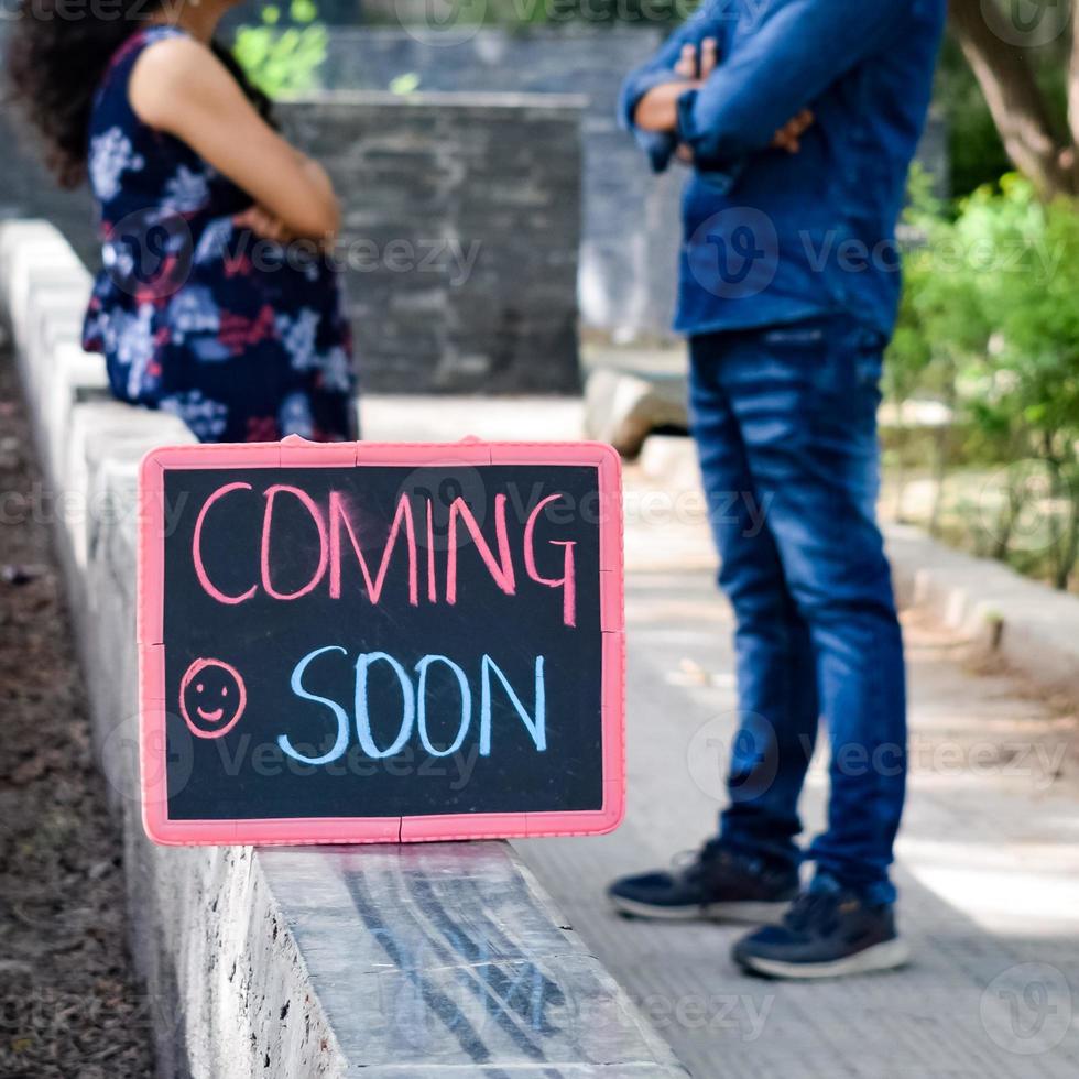 Indian couple posing for maternity baby shoot. The couple is posing in a lawn with green grass and the woman is falunting her baby bump in Lodhi Garden in New Delhi, India photo