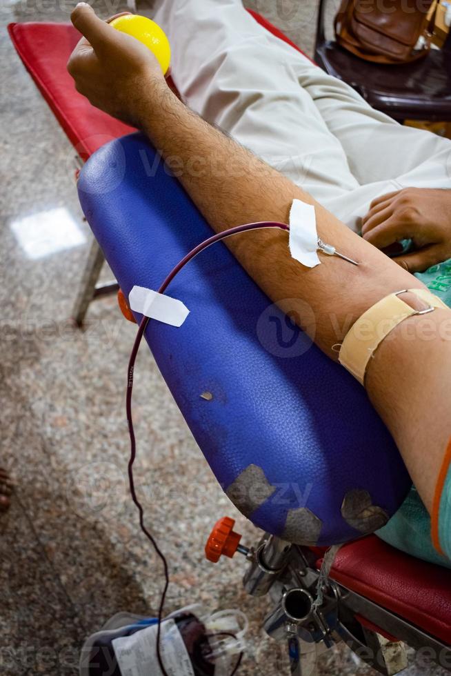 donante de sangre en el campamento de donación de sangre sostenido con una pelota hinchable en la mano en el templo balaji, vivek vihar, delhi, india, imagen para el día mundial del donante de sangre el 14 de junio de cada año, campamento de donación de sangre foto