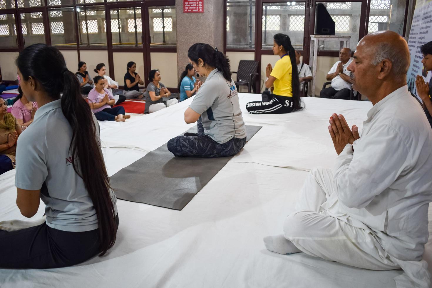 New Delhi, India, June 19 2022 -Group Yoga exercise session for people of different age groups in Balaji Temple, Vivek Vihar, International Yoga Day, Big group of adults attending yoga class in temple photo
