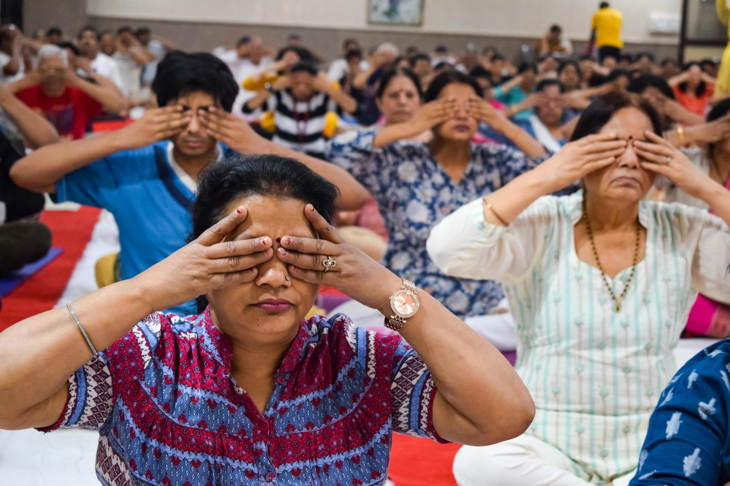 New Delhi, India, June 19 2022 -Group Yoga exercise session for people of different age groups in Balaji Temple, Vivek Vihar, International Yoga Day, Big group of adults attending yoga class in temple photo