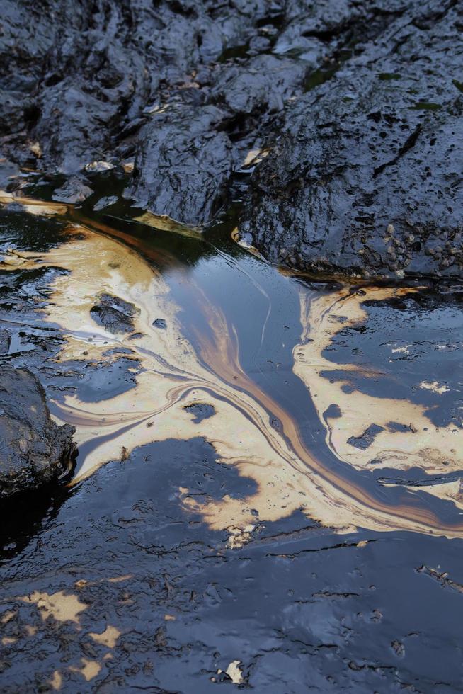 crude oil spill on the stone at the beach photo