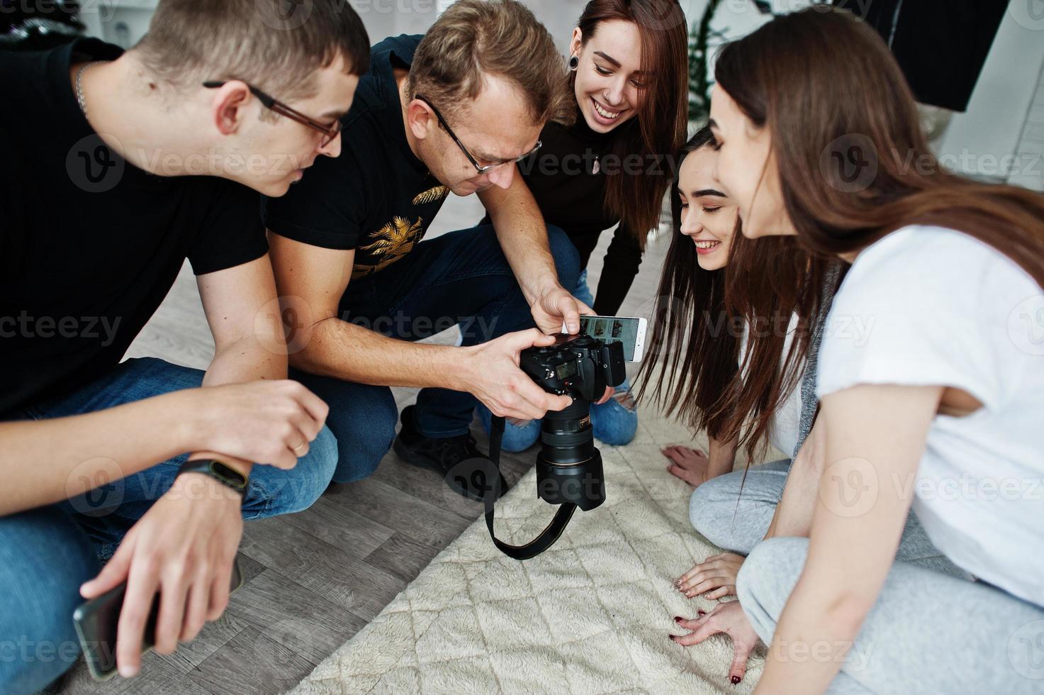 The team of photographers showing pictures on screen of camera for twins models girls on studio. Professional photographer on work. photo