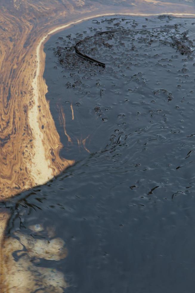 crude oil spill on the stone at the beach photo