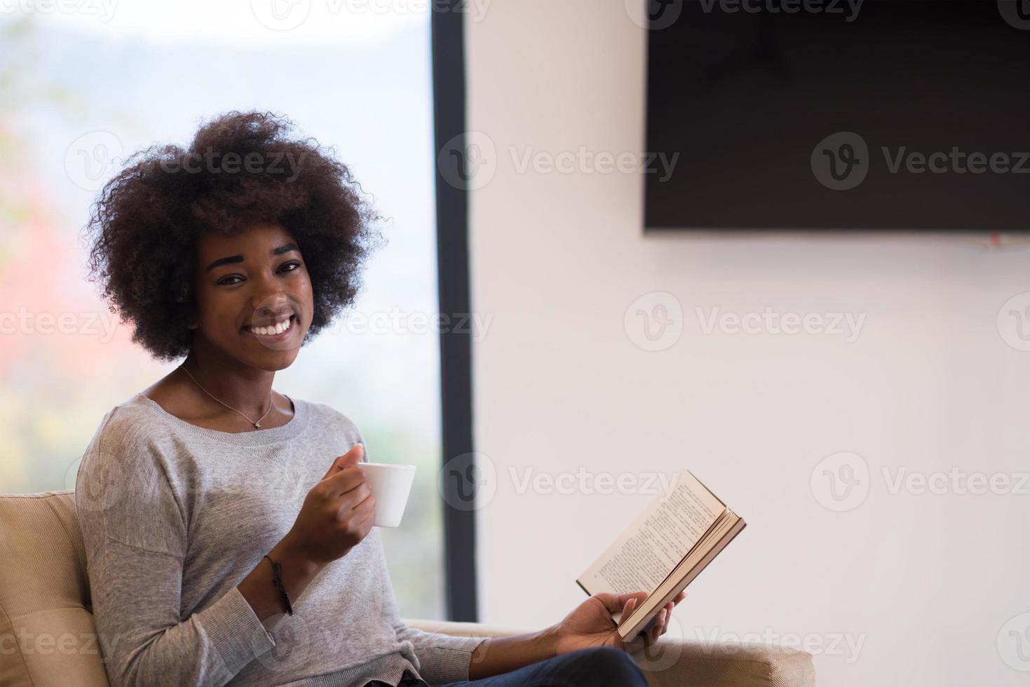 black woman reading book  in front of fireplace photo
