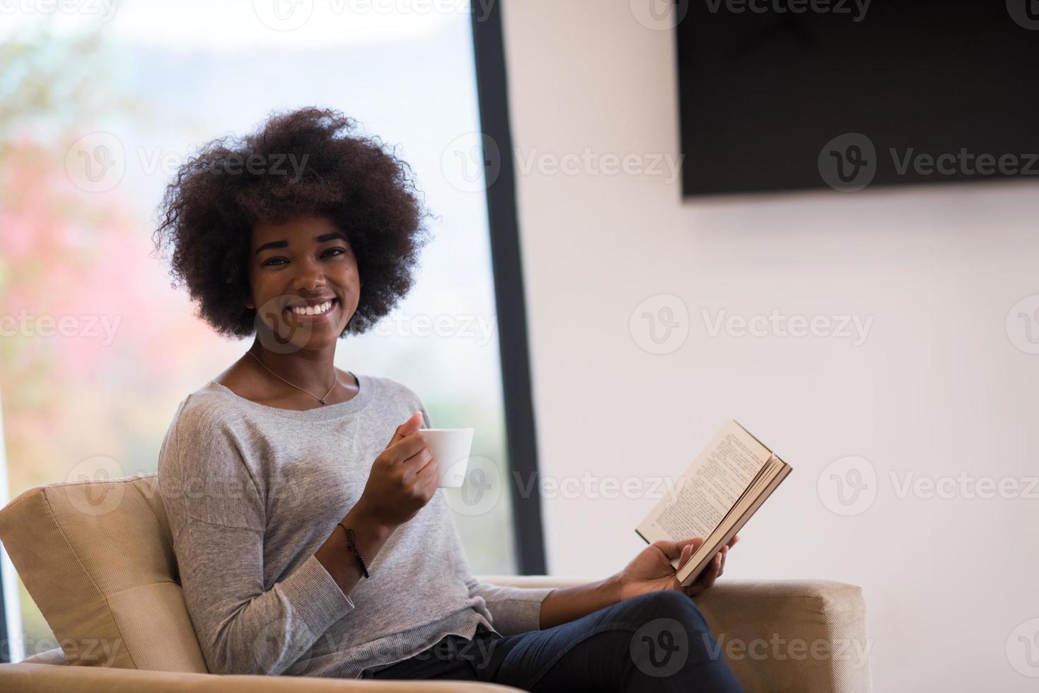 black woman reading book  in front of fireplace photo