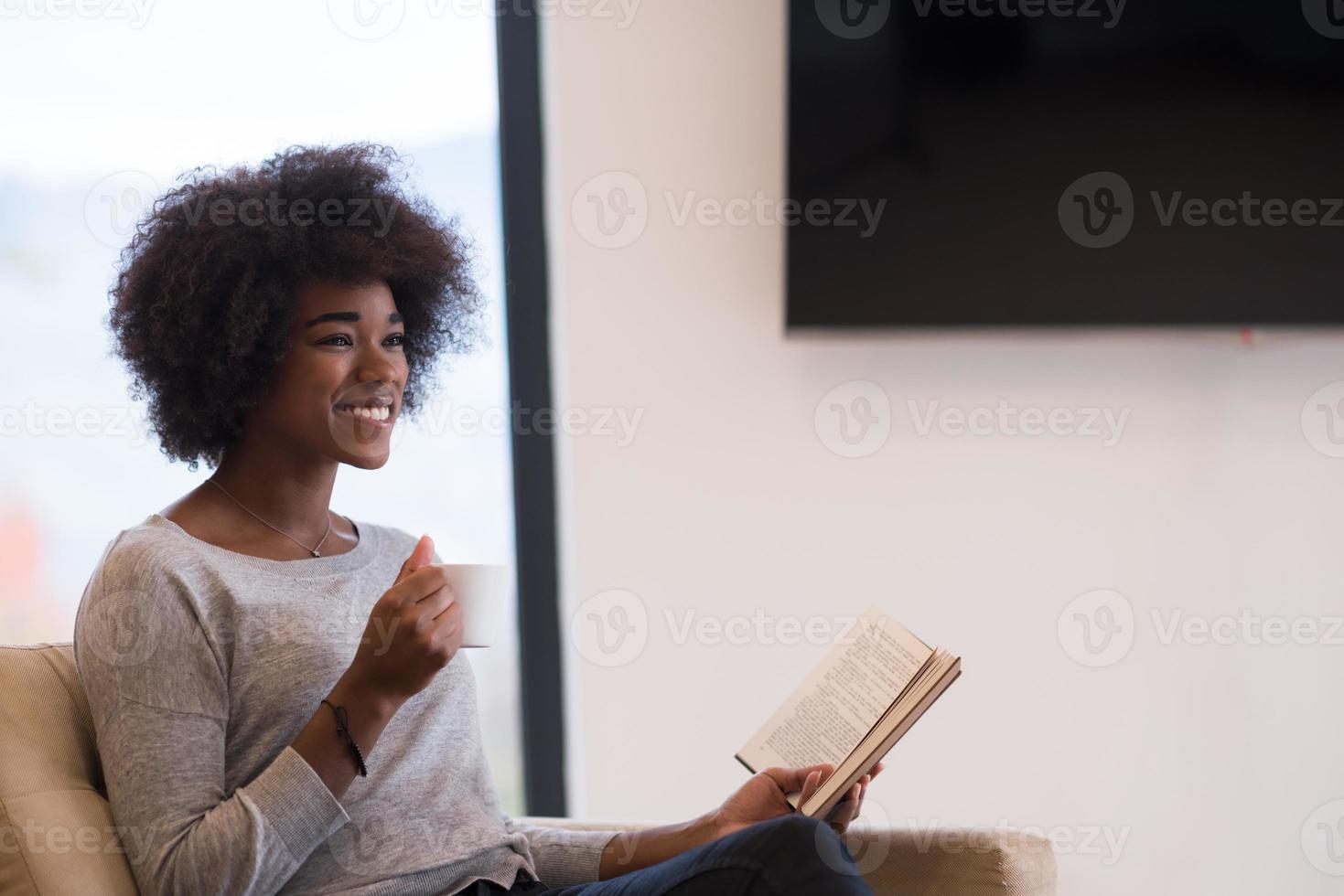 black woman reading book  in front of fireplace photo