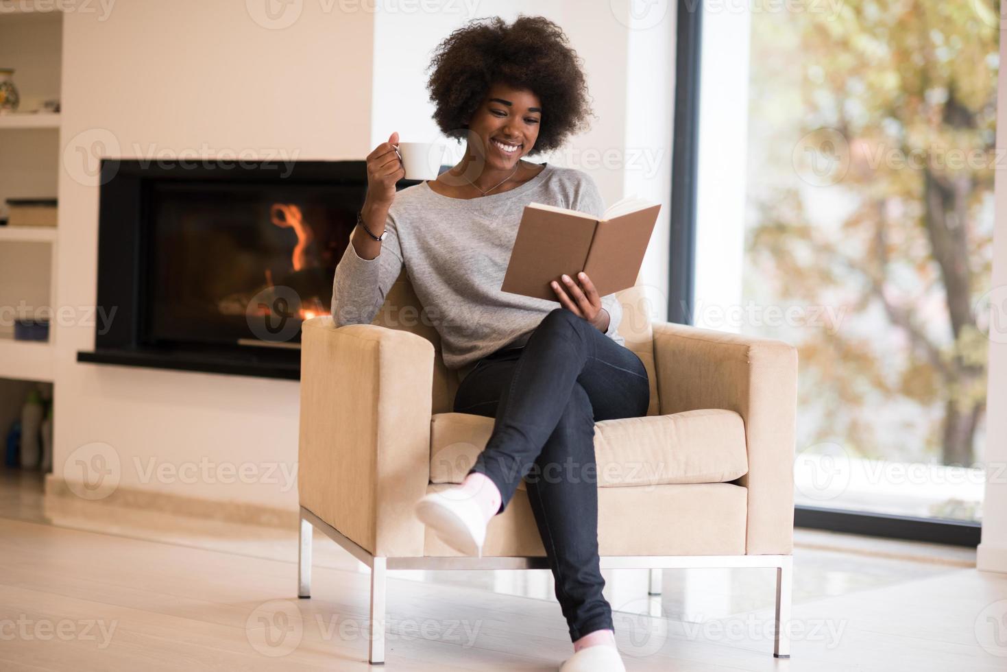 mujer negra leyendo un libro frente a la chimenea foto