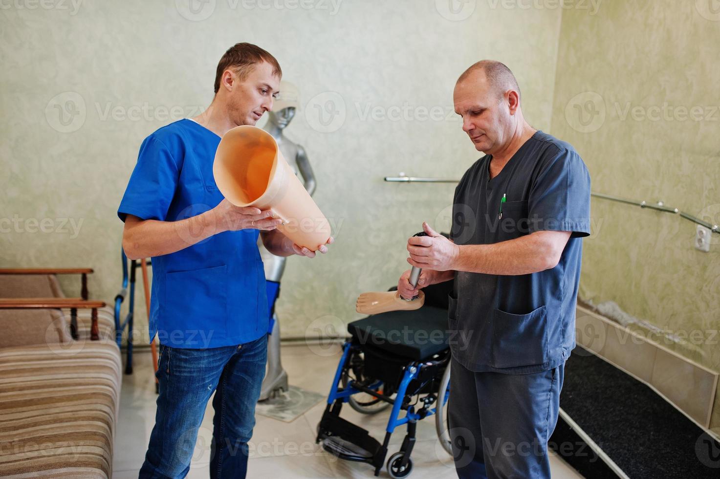 Two prosthetist man workers with prosthetic leg working in laboratory. photo