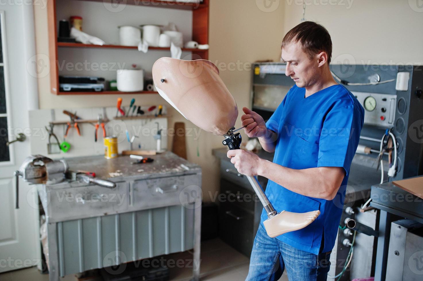 Prosthetist man making prosthetic leg while working in laboratory. photo
