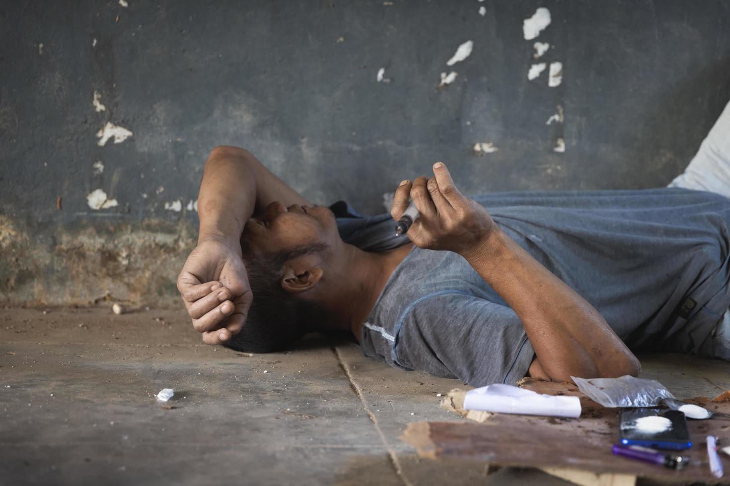 Human hand of a drug addict and a syringe with narcotic syringe lying on the floor. Anti drug concept. photo