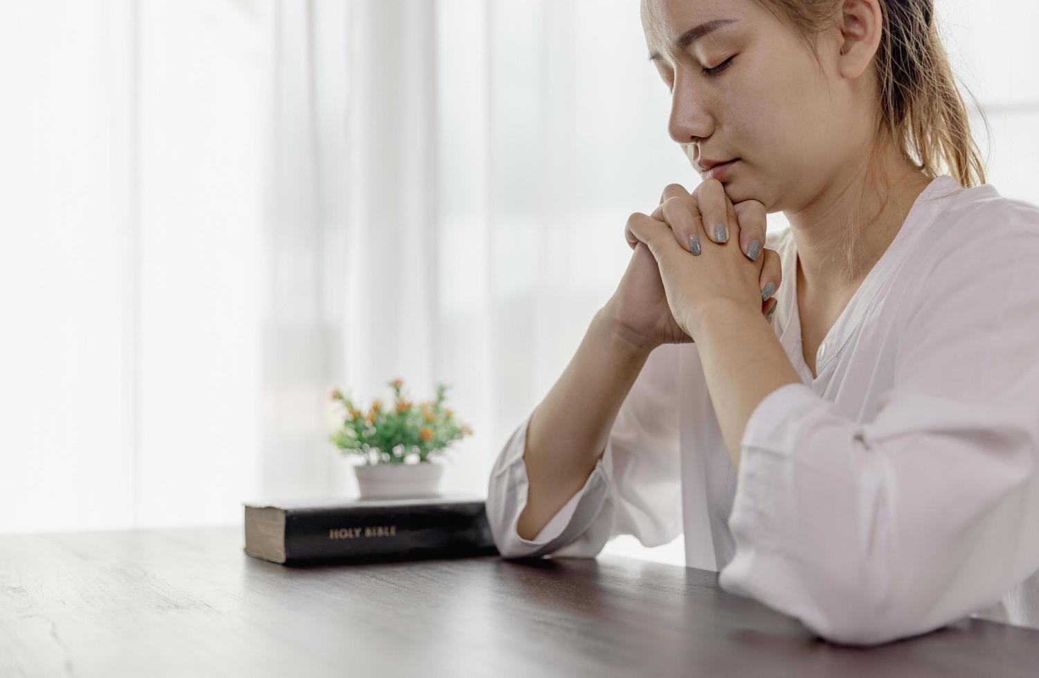 mano de mujer mientras reza por la religión cristiana, mujer casual rezando con una cruz, concepto de religión. foto