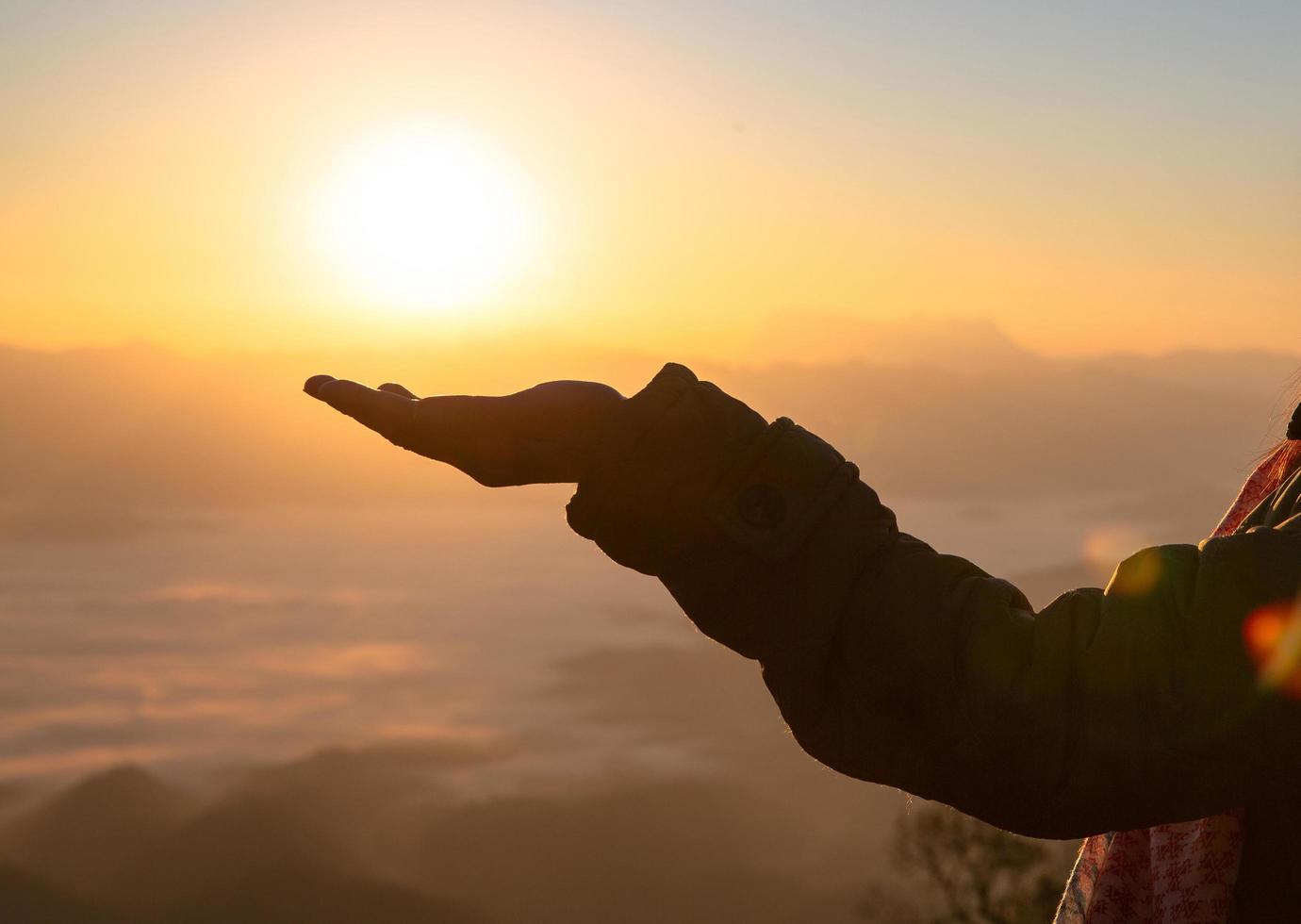 el sol en una mano de mujer. silueta de mano sosteniendo el sol, concepto de oración. foto