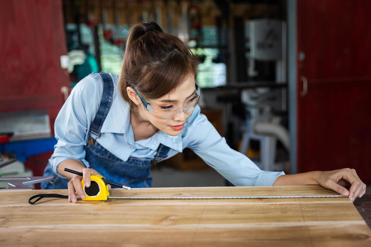 happy attractive hardworking middle aged professional female carpenter worker looking and choosing wood in the workshop. photo