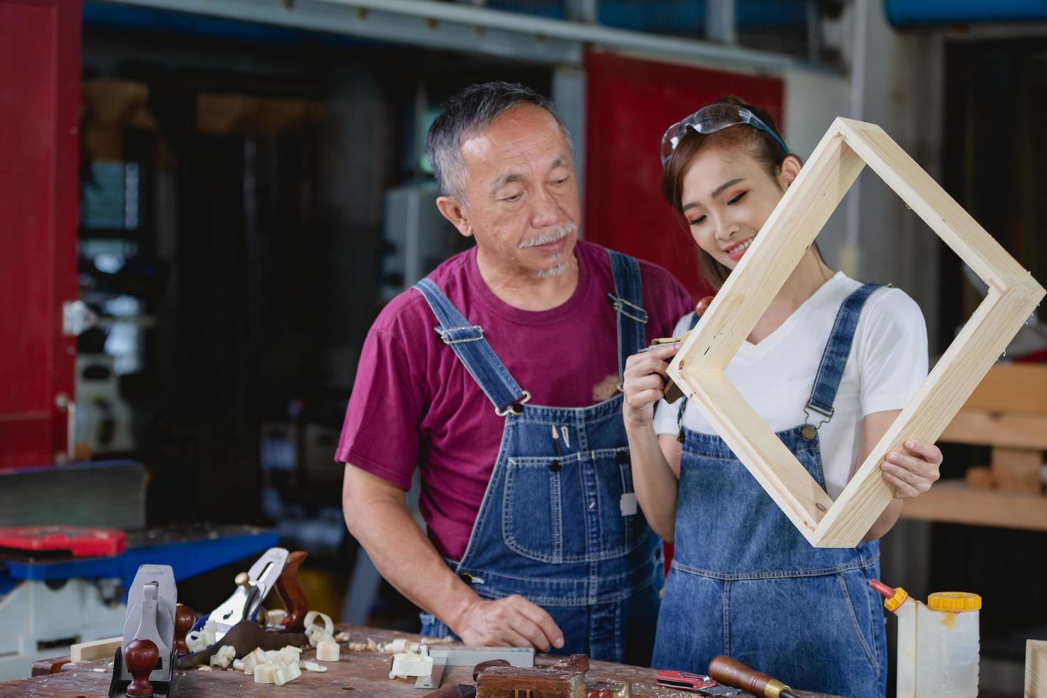 Two professional carpenters works in her own woodworking shop. Carpenter work on wood plank in workshop. small business concept. photo