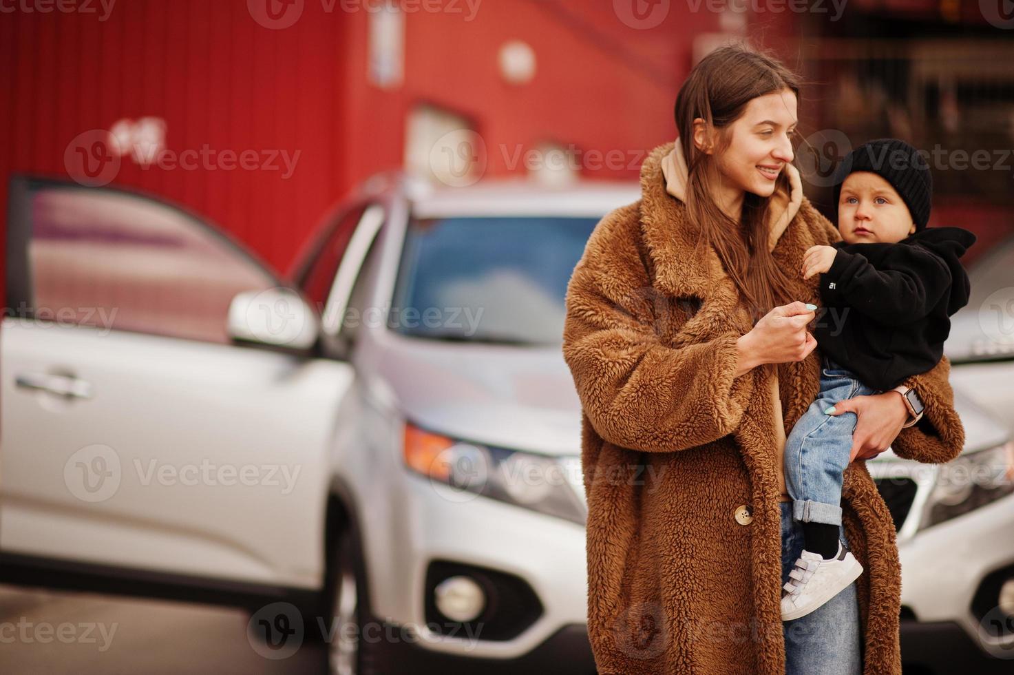 la joven madre y el niño se paran cerca de su auto todoterreno. concepto de conducción segura. foto