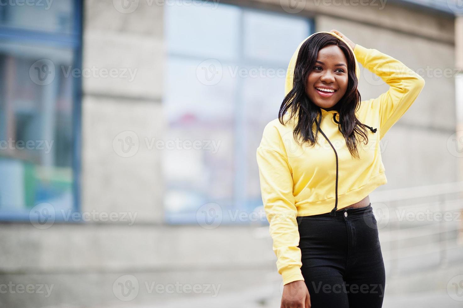 Hipster african american girl wearing yellow hoodie posing at street. photo