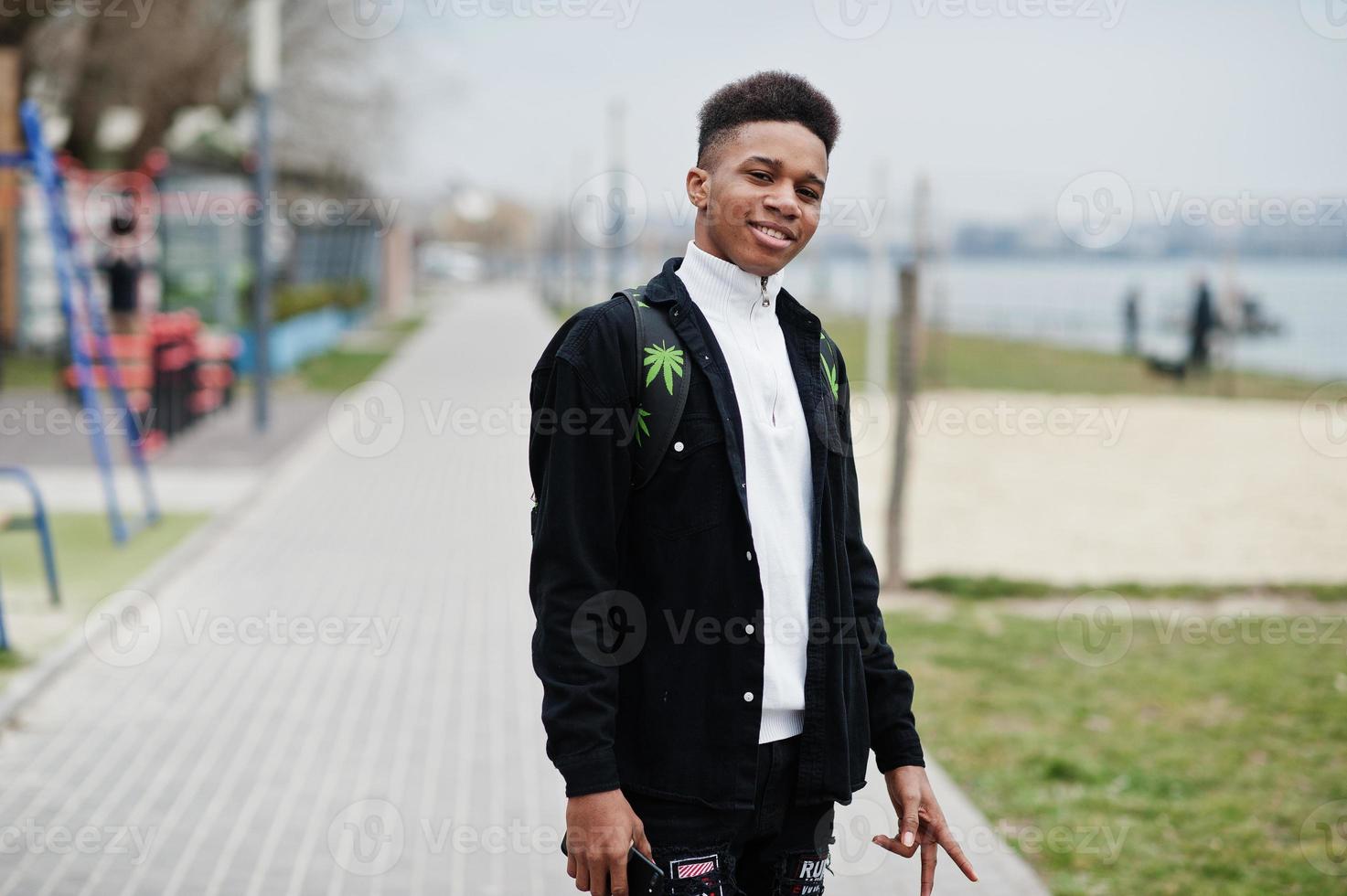 Young millennial african boy walking in city. Happy black man with marijuana backpack. Generation Z concept. photo