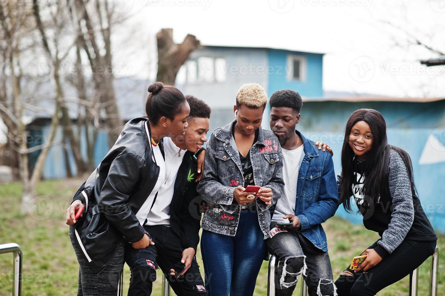 Young millennials african friends with mobile phones. Happy black people having fun together. Generation Z friendship concept. photo