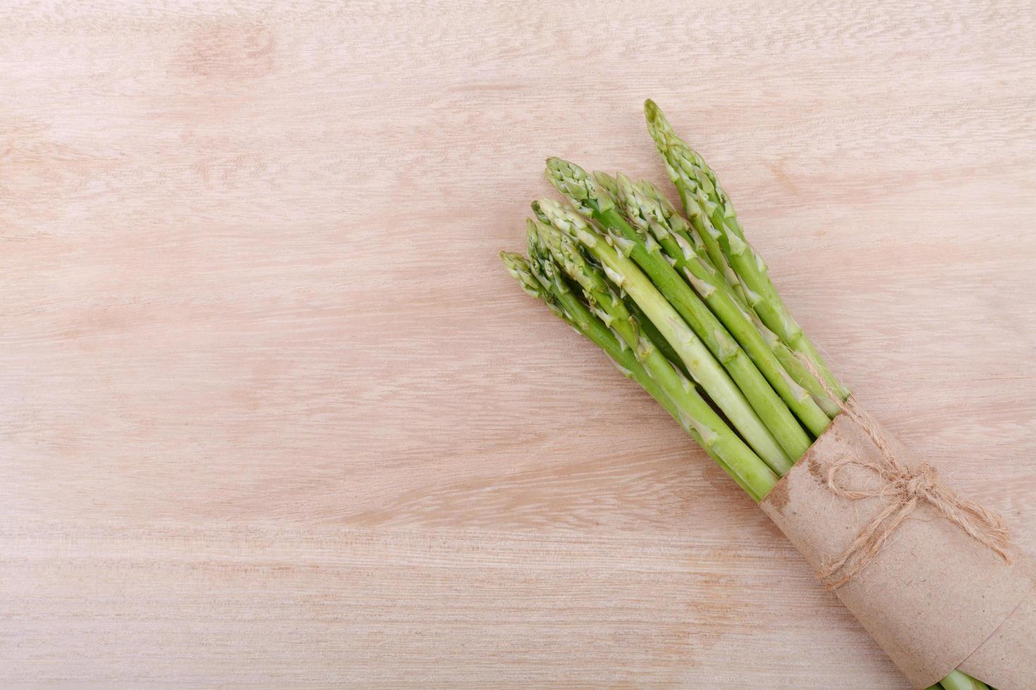 uncooked green asparagus tied with twine from above on wooden photo