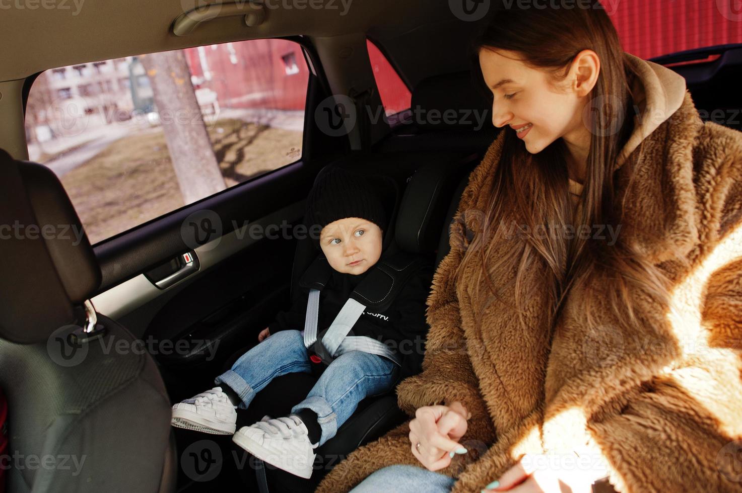 Young mother and child in car. Baby seat on chair. Safety driving concept. photo