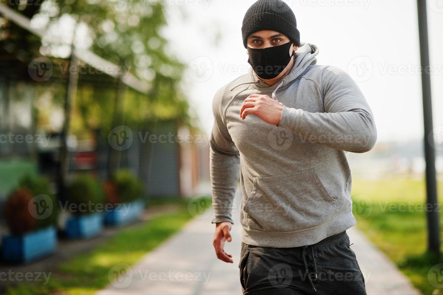 Portrait sports arabian man in black medical face mask run outdoor during coronavirus quarantine. photo