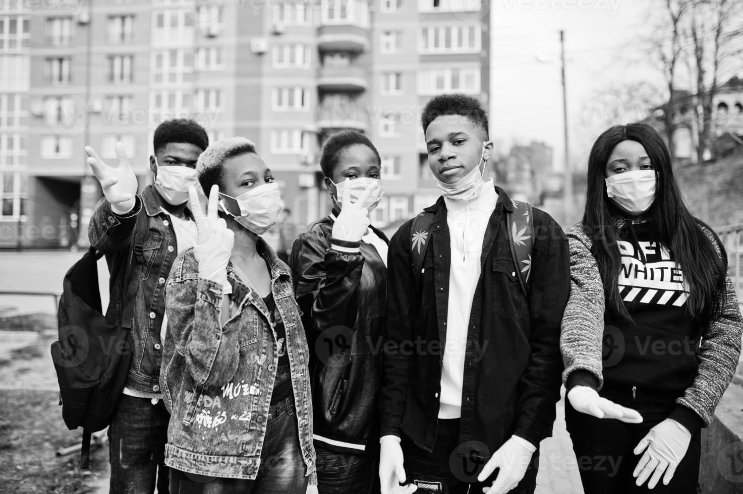 Group of african teenagers friends against empty street with building wearing medical masks protect from infections and diseases coronavirus virus quarantine. photo