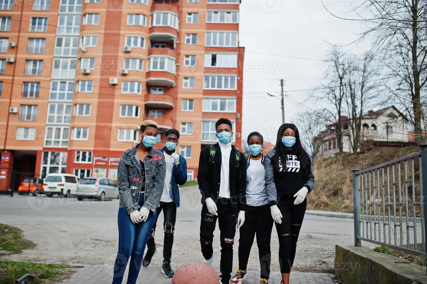 Group of african teenagers friends against empty street with building wearing medical masks protect from infections and diseases coronavirus virus quarantine. photo