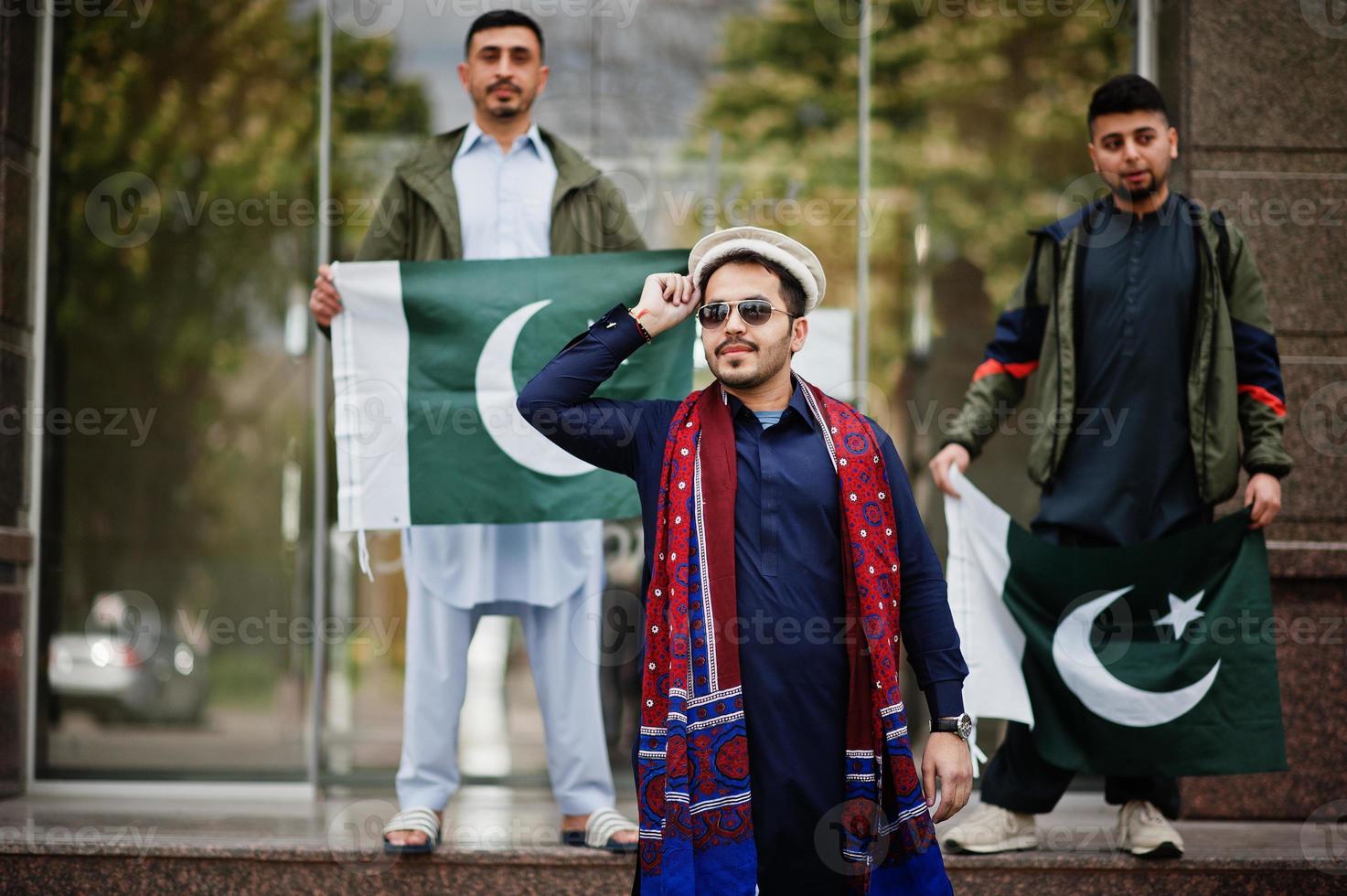 grupo de hombres paquistaníes vestidos con ropa tradicional salwar kameez o kurta con banderas de pakistán. foto