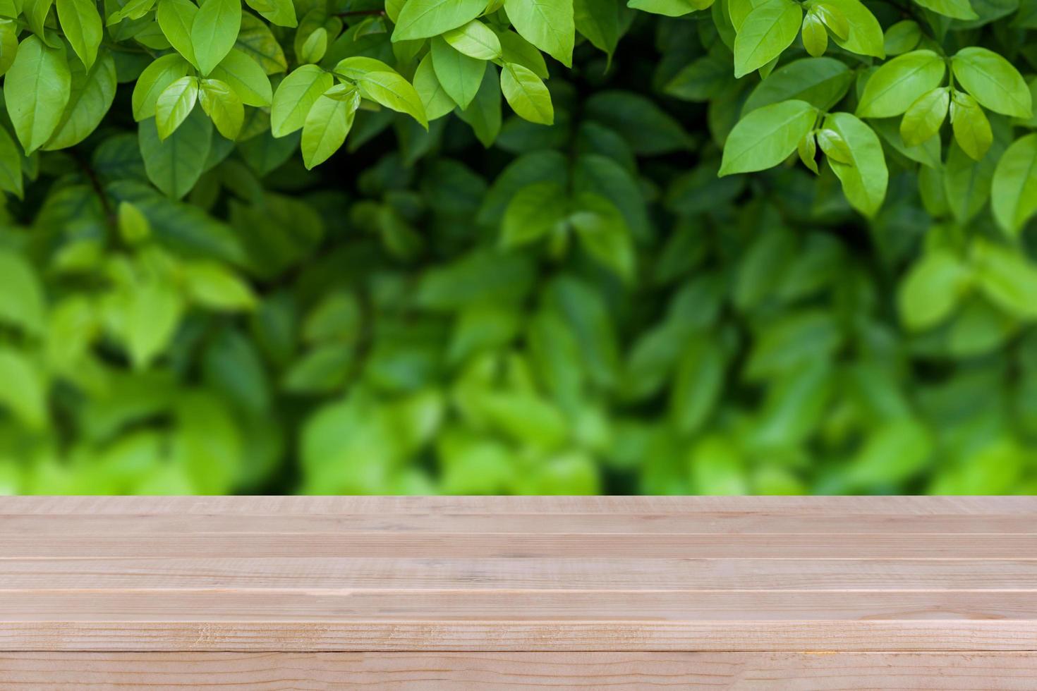 mesa de madera marrón sobre fondo de naturaleza verde abstracto bokeh - se puede utilizar para montar o mostrar sus productos foto