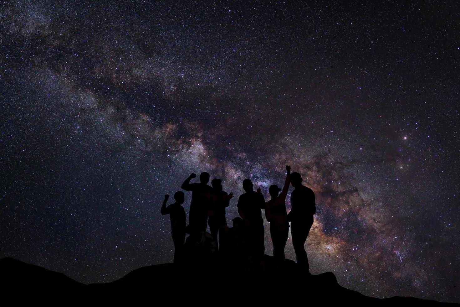 Landscape with milky way, Night sky with stars and silhouette of happy people standing on the mountain, Long exposure photograph, with grain photo