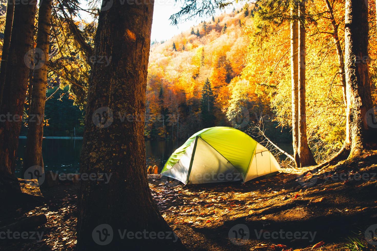 Tent on shore by Bateti lake outdoors in fall in sunny beautiful autumn morning . Relaxation and travel outdoors in fall season concept photo