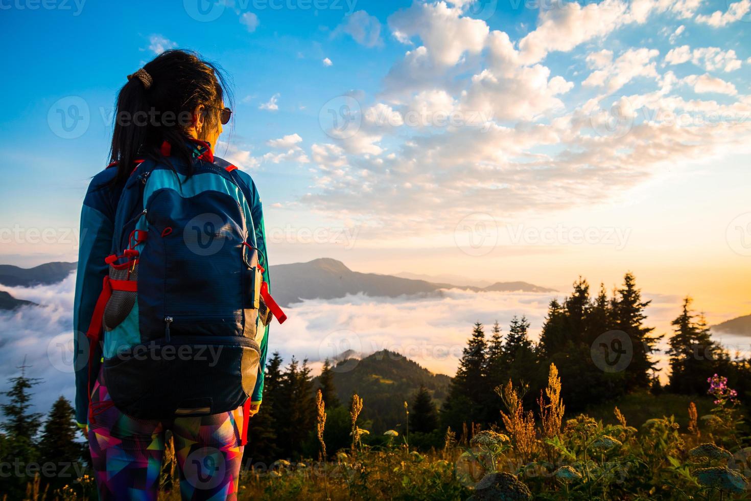 Back view hiker backpacker on forest trail enjoy dramatic sunset over clouds in remote caucasus mountains warm summer evening photo