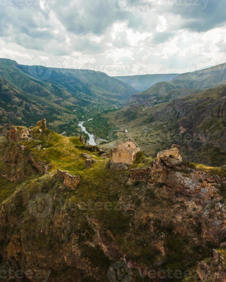 Aerial view historical Tmogvi fortress ruins with old wall on hilltop and church remains in scenic valley in summer photo