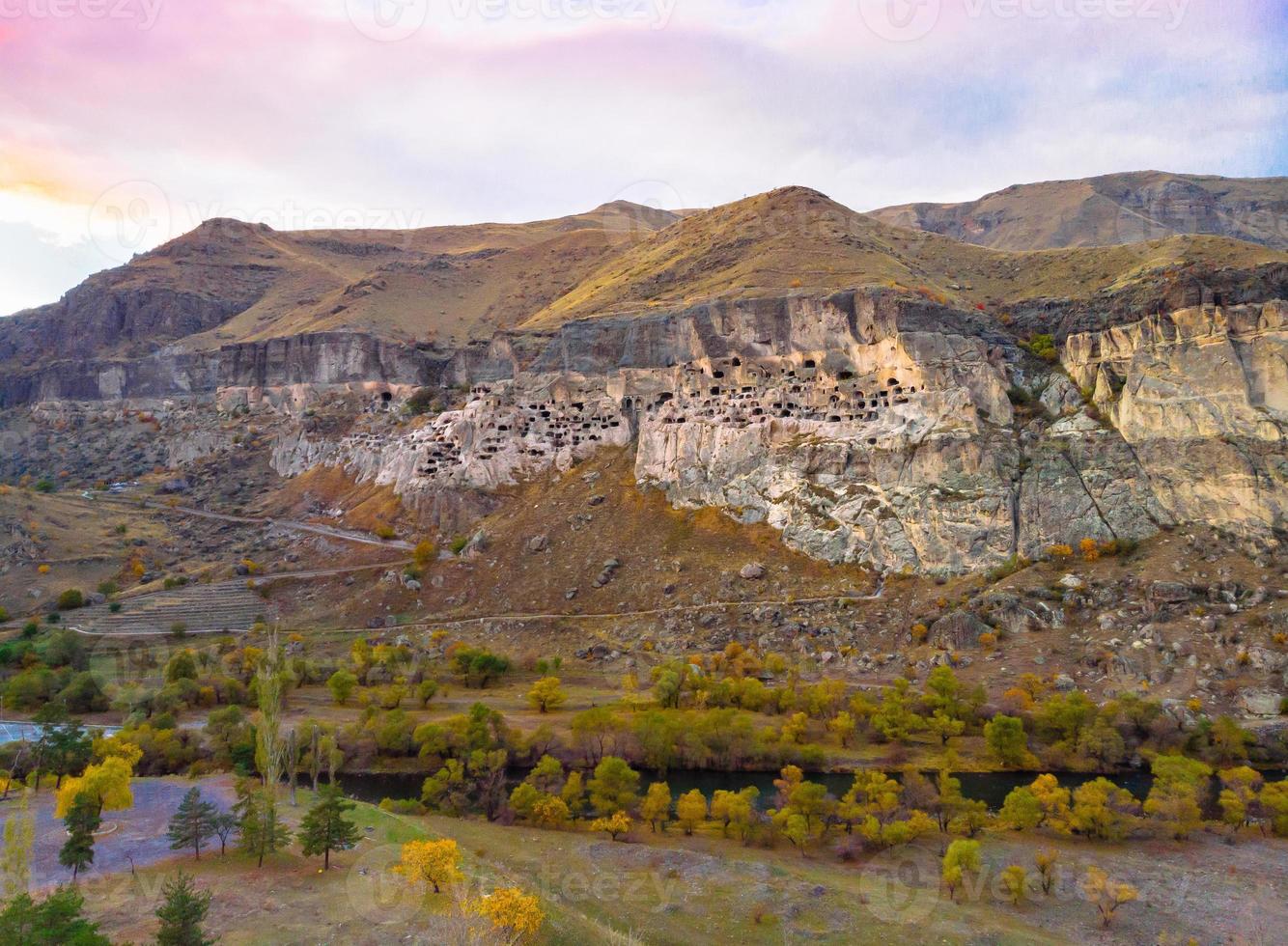 Aerial perspective of Vardzia-cave city from above with paravani river and autumn nature in foreground. Historical unesco sites Georgia. photo