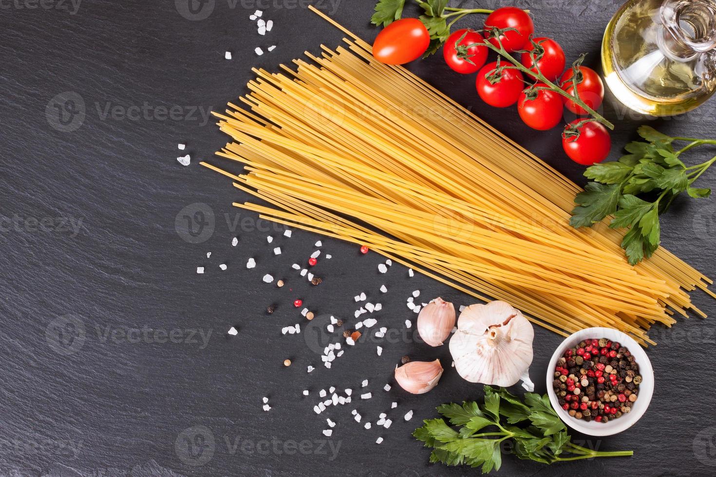 Pasta and cooking ingredients on black slate background. photo