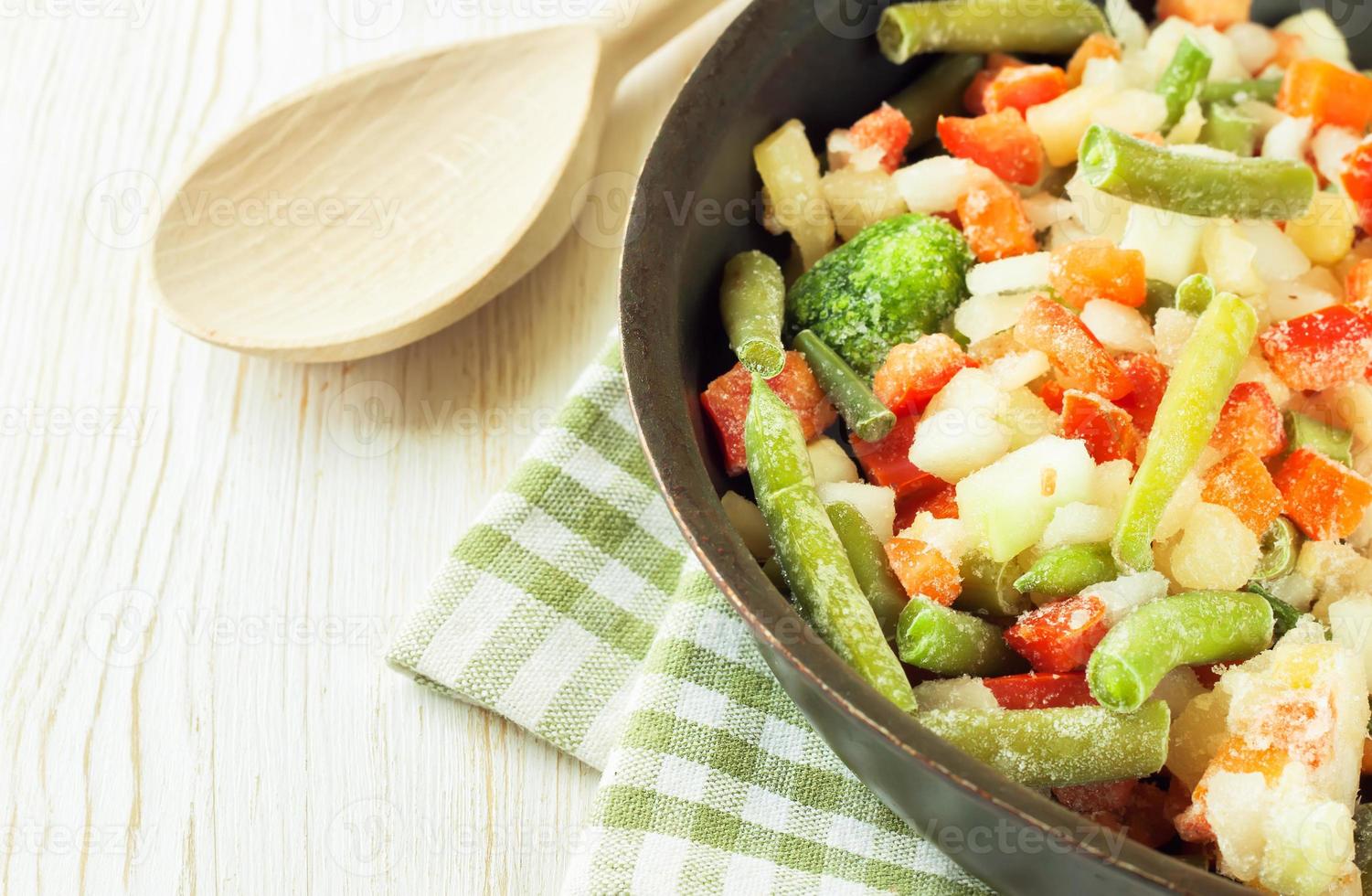 Mixture of frozen vegetables on white wooden background photo