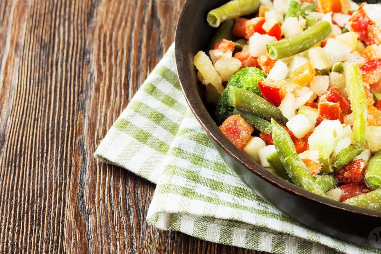 mezcla de verduras congeladas sobre fondo de madera marrón foto