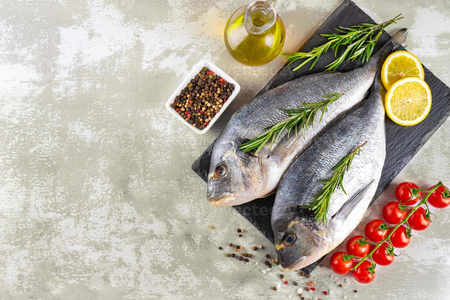 mariscos, pescado fresco dorado e ingredientes para cocinar sobre fondo gris. vista superior con espacio de copia foto