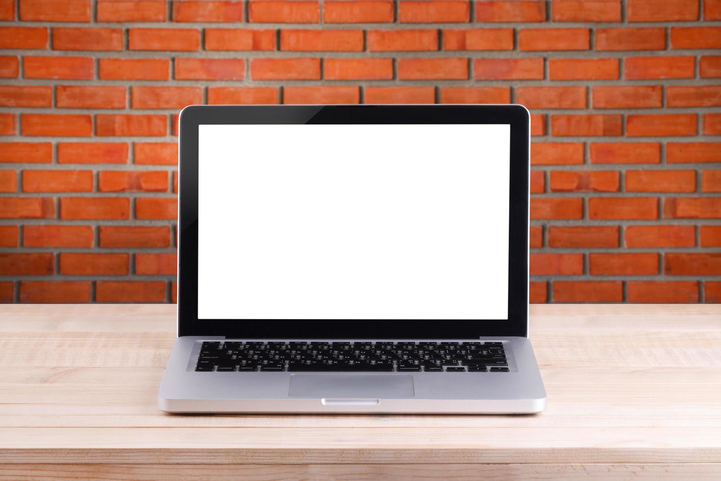 Front view of the laptop is on the work table brick background photo