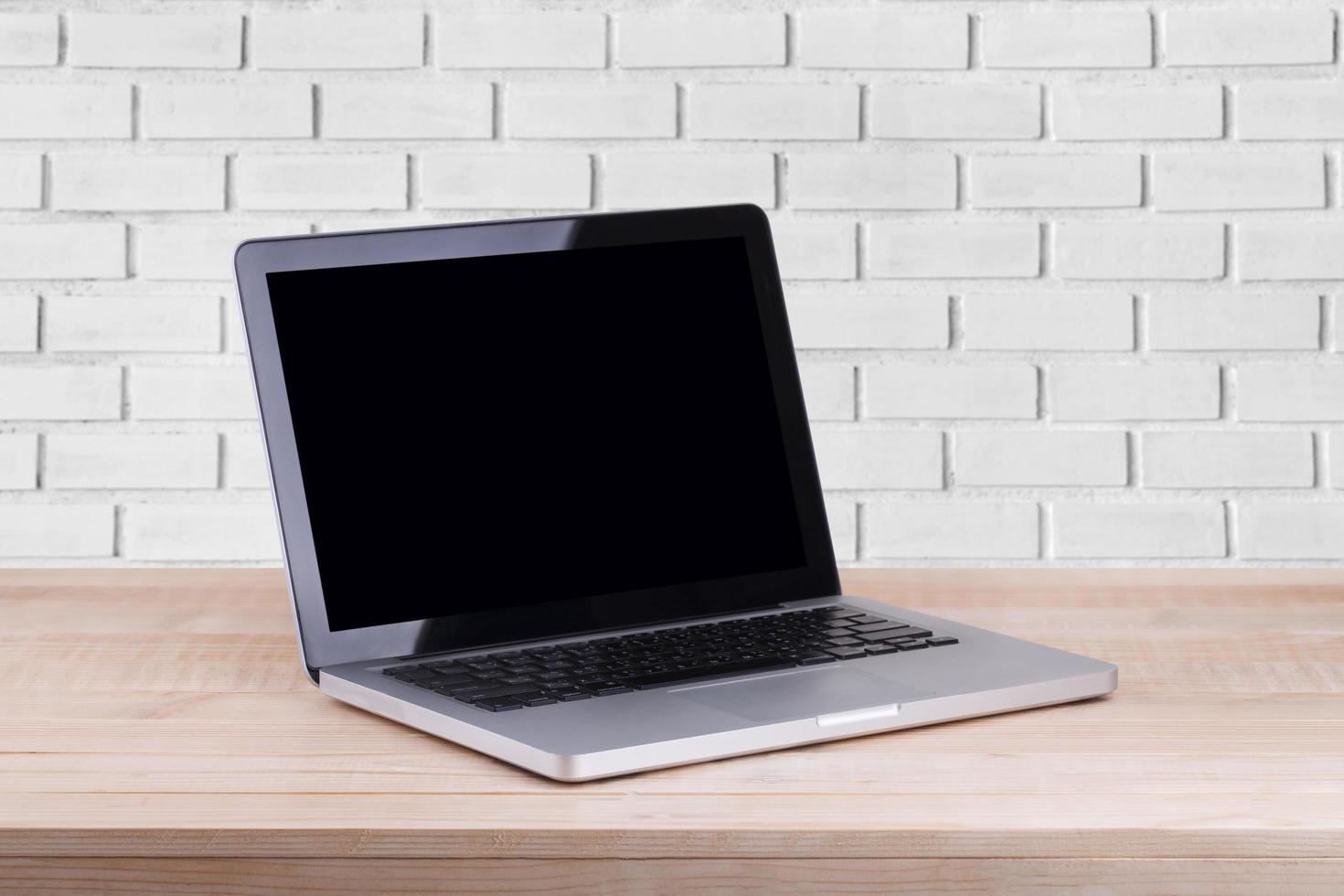 Front view of the laptop is on the work table brick background photo