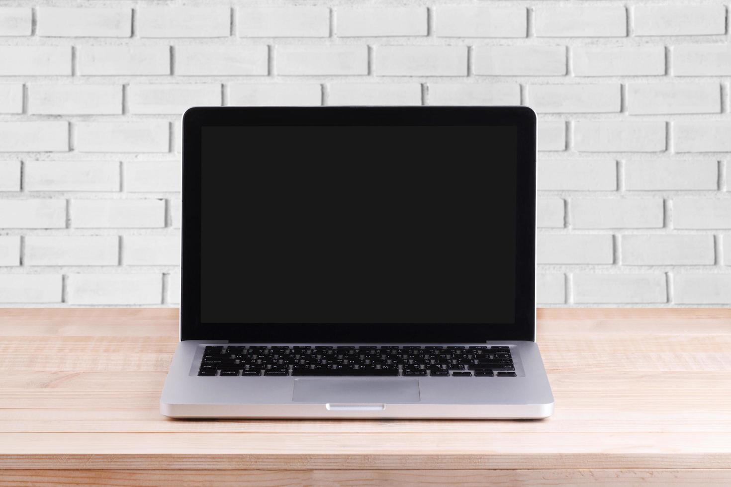 Front view of the laptop is on the work table brick background photo