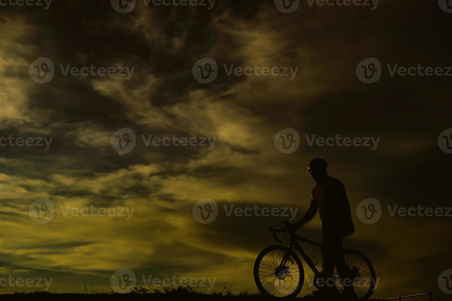 silueta de un hombre guapo montando en bicicleta al atardecer, concepto de hombre deportivo foto