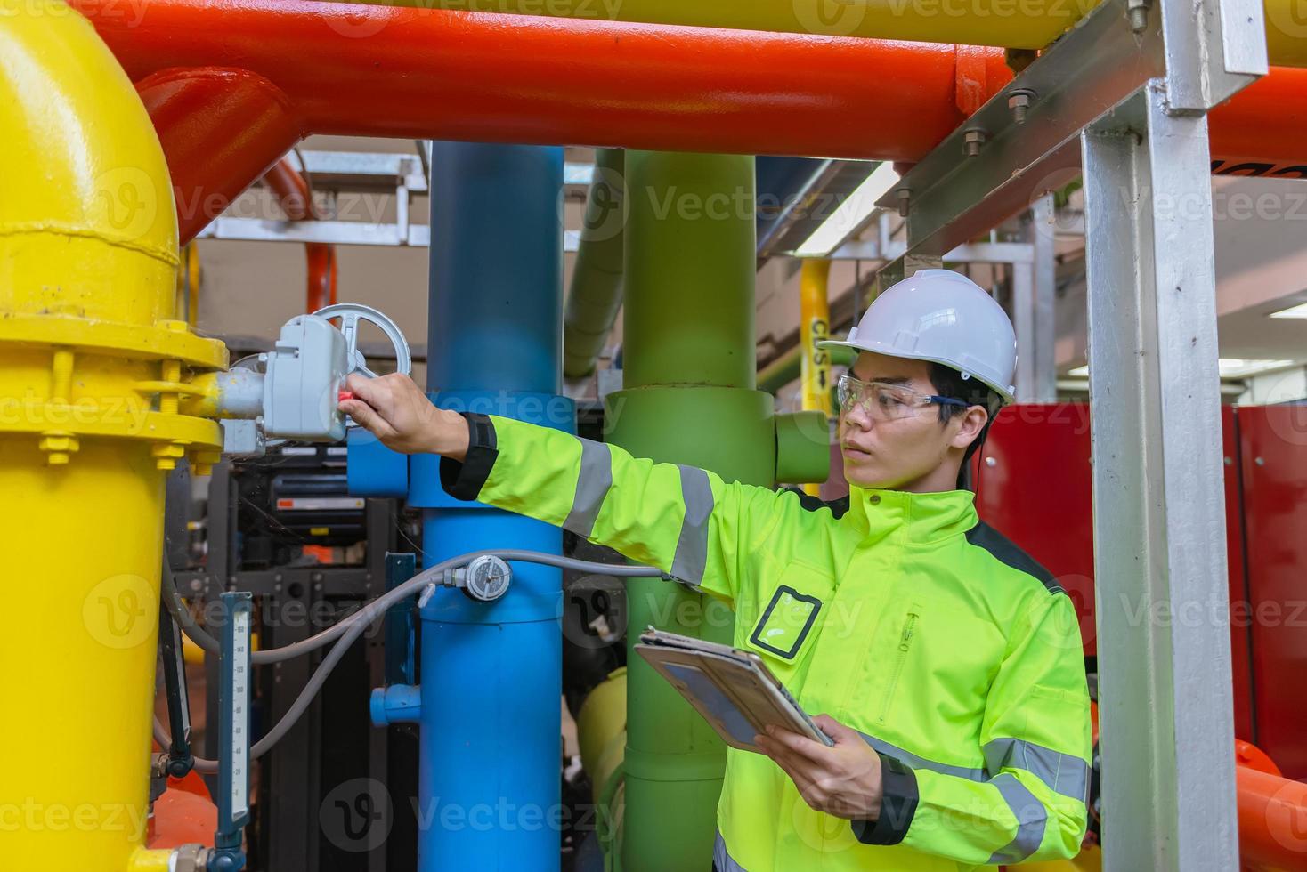 Asian engineer wearing glasses working in the boiler room,maintenance checking technical data of heating system equipment,Thailand people photo