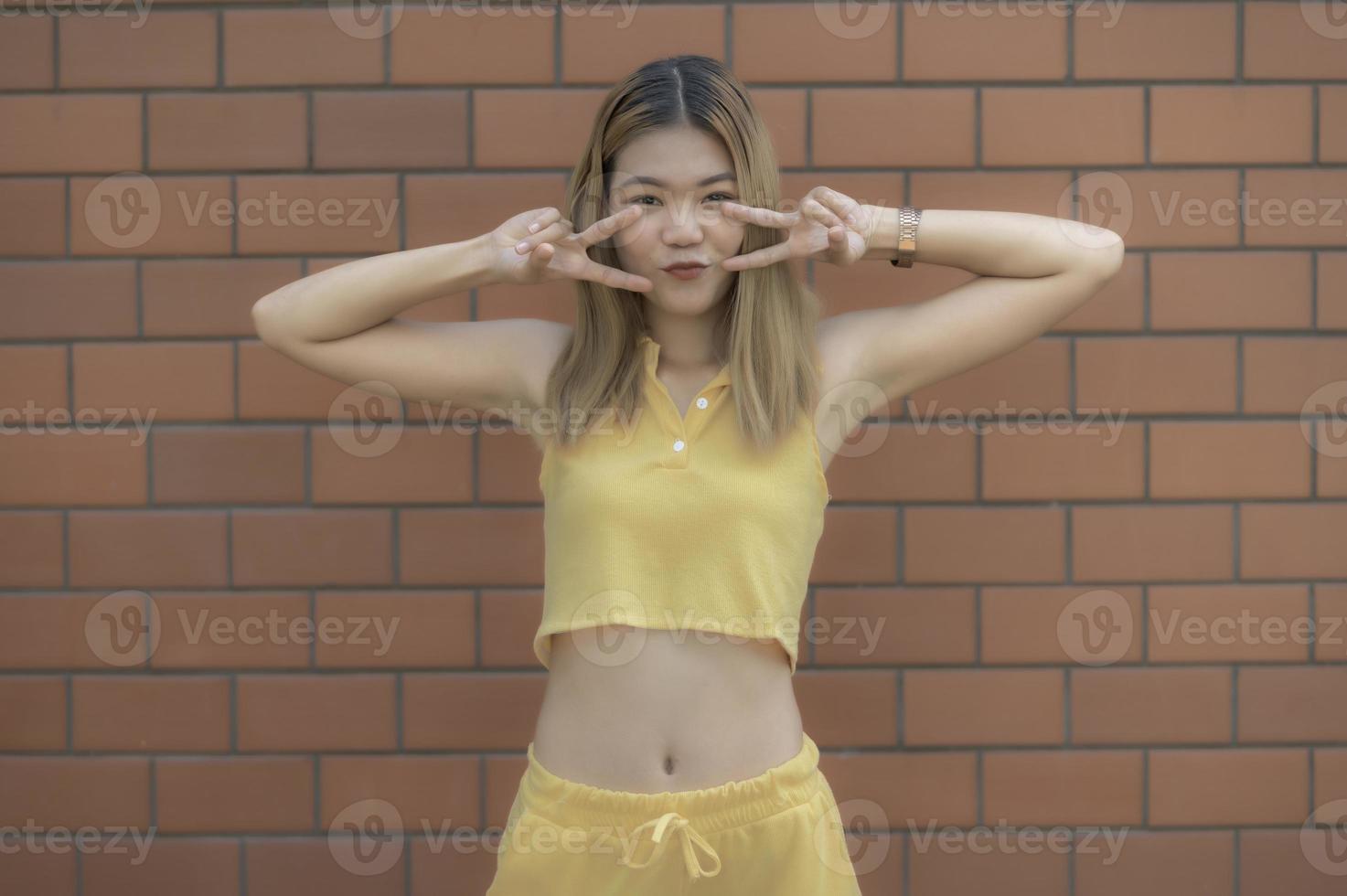 retrato de chica hipster en el fondo de la pared de ladrillo, hermosa mujer asiática posar para tomar una foto, estilo kawaii foto