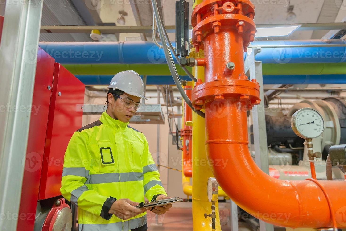 Asian engineer wearing glasses working in the boiler room,maintenance checking technical data of heating system equipment,Thailand people photo