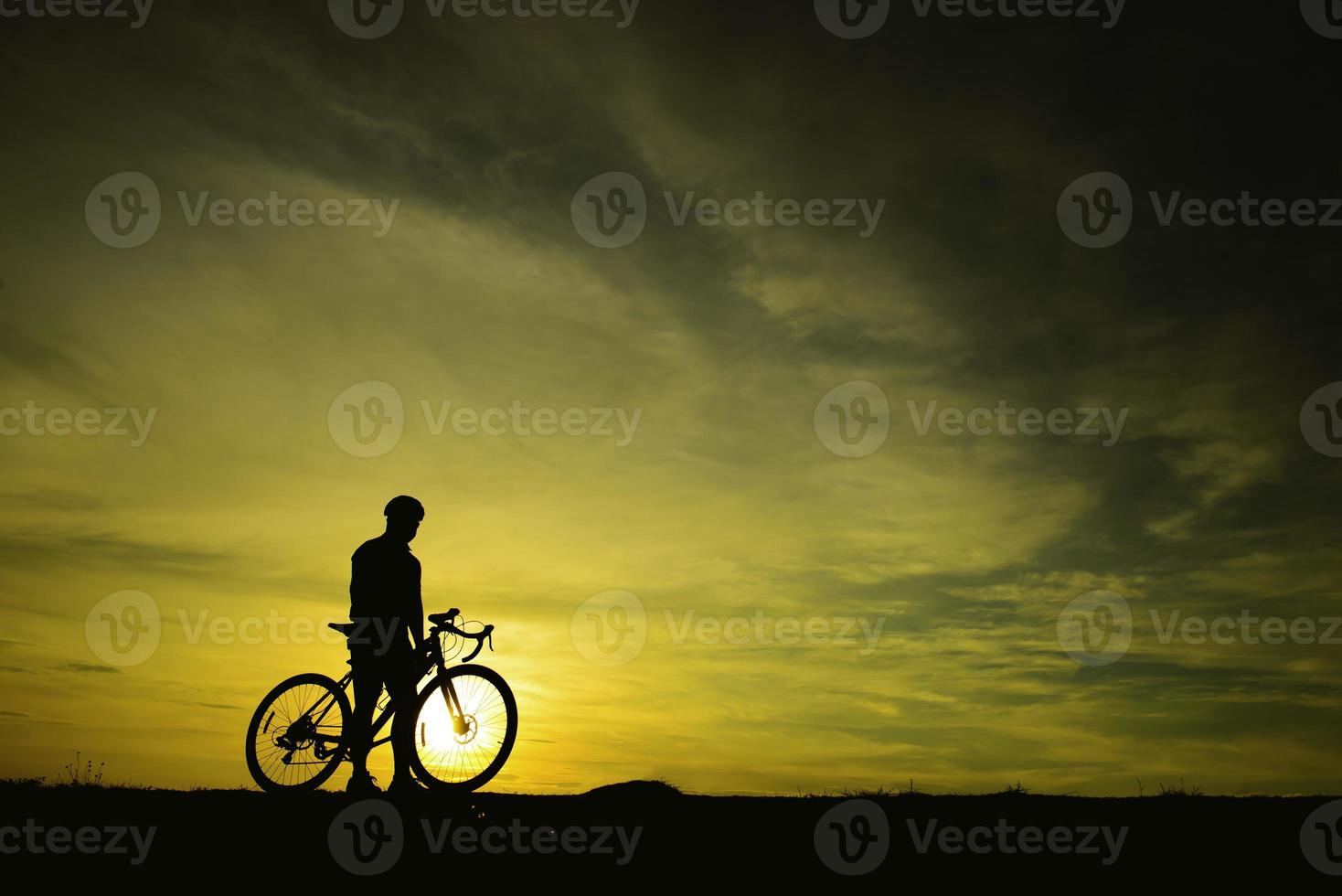 silueta de un hombre guapo montando en bicicleta al atardecer, concepto de hombre deportivo foto