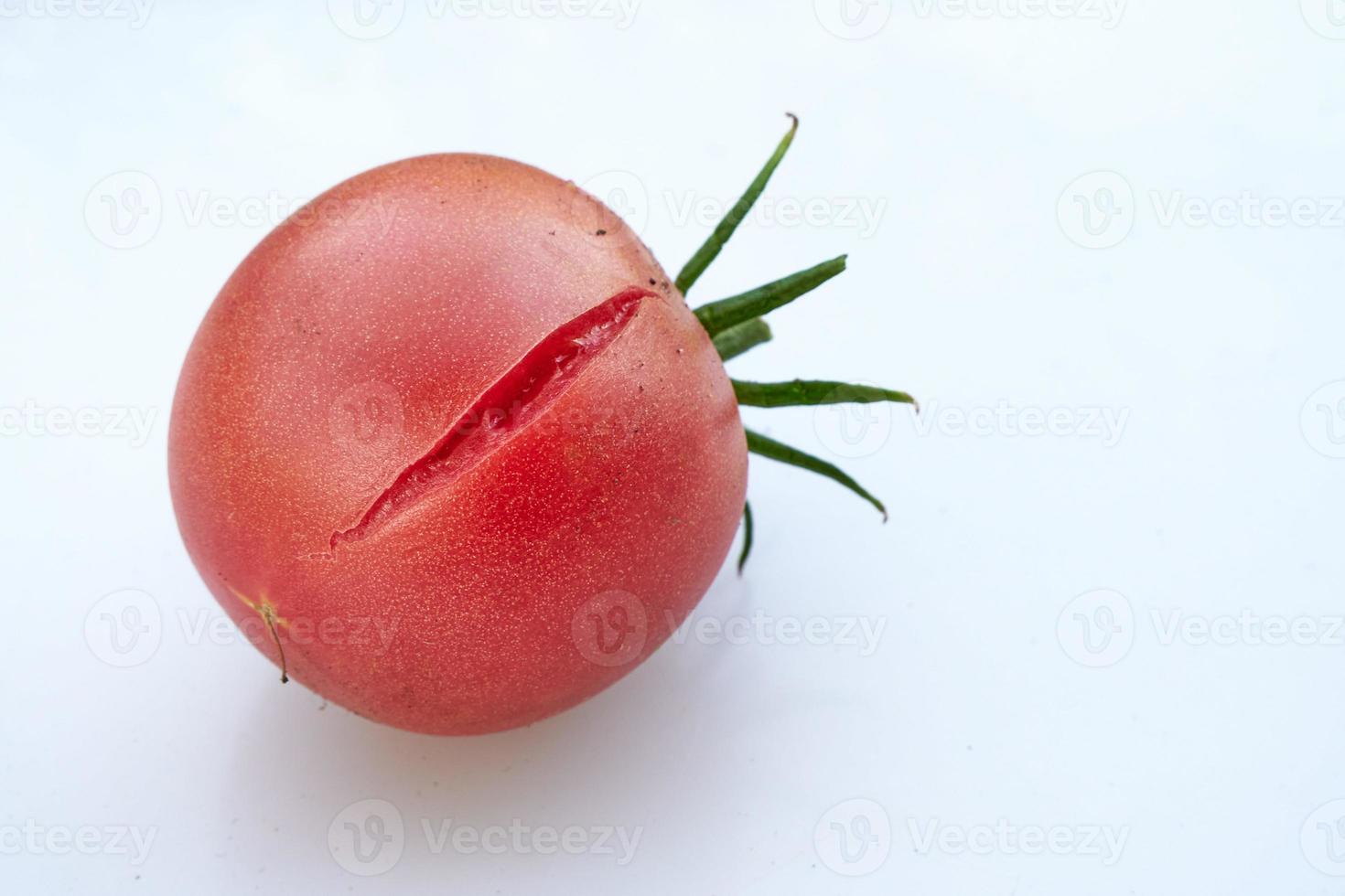 Cracked, juicy, red tomato on white background. photo